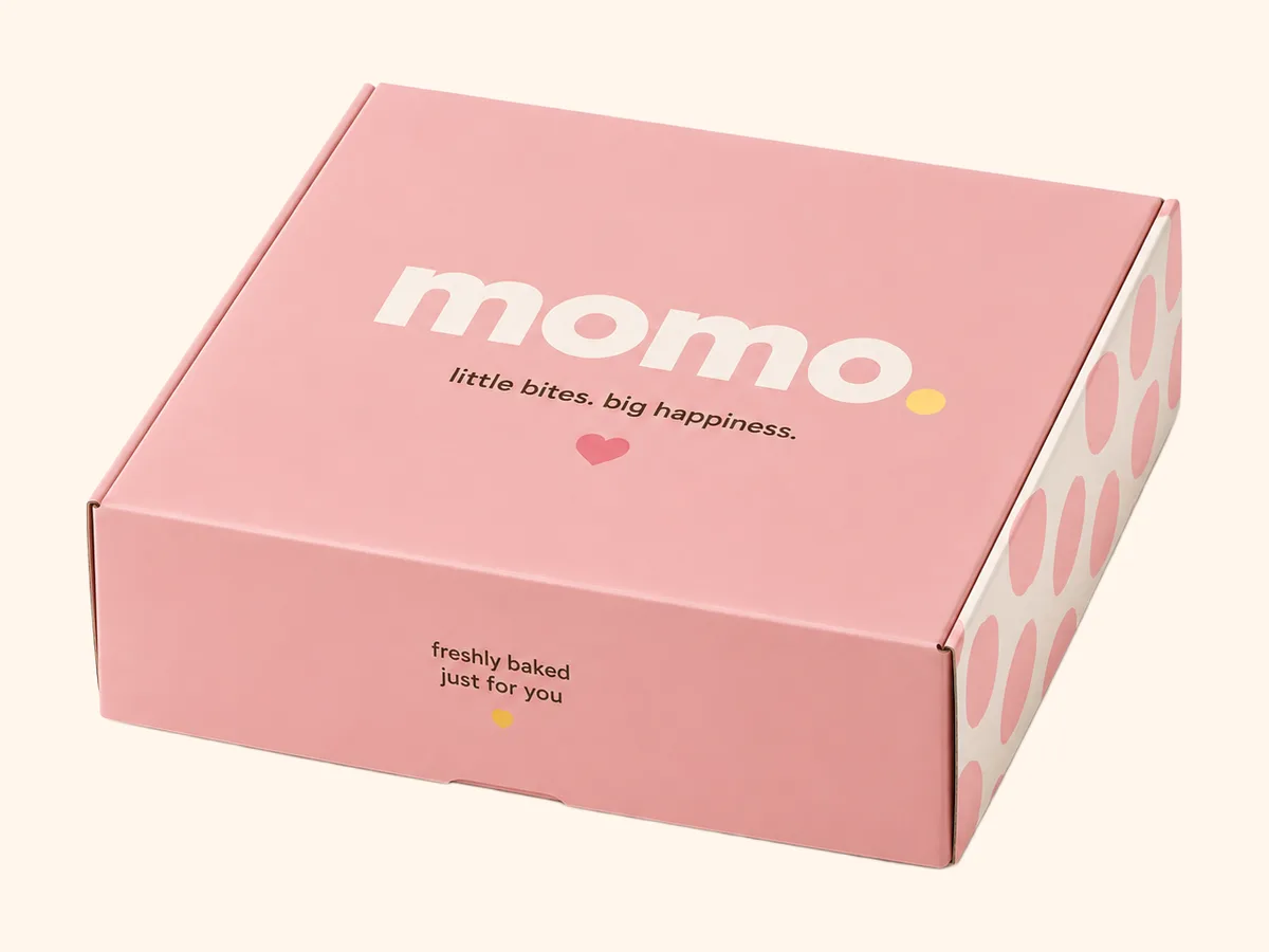 The pink six-box, closed, with the wordmark and the polka-dot side panel